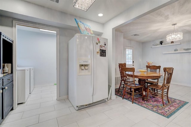 dining space with an inviting chandelier, washer and clothes dryer, visible vents, light tile patterned flooring, and baseboards