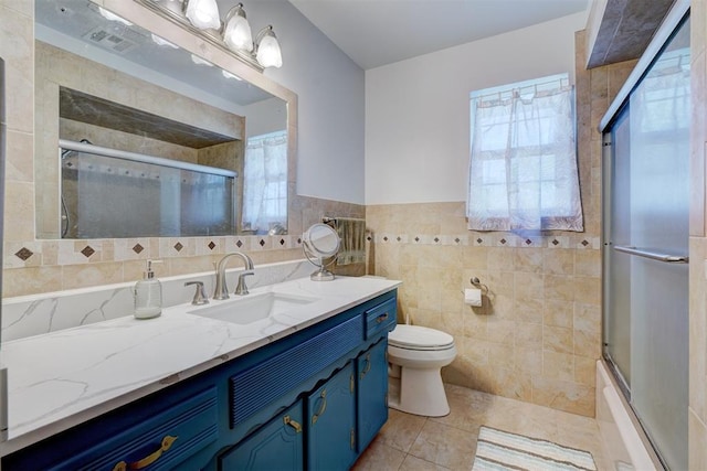 bathroom featuring toilet, a healthy amount of sunlight, tile patterned flooring, and tile walls