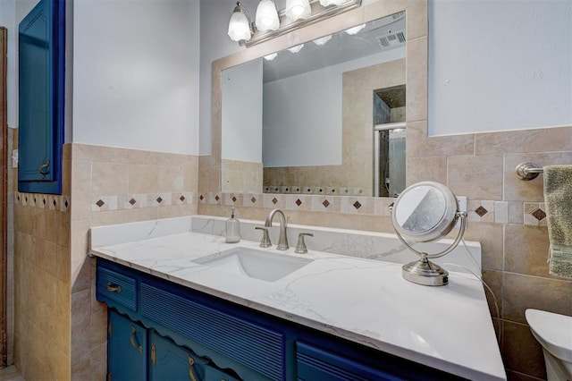 bathroom with vanity, wainscoting, a stall shower, and tile walls