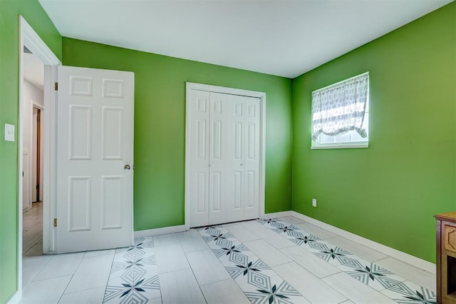 unfurnished bedroom with a closet, baseboards, and light tile patterned floors