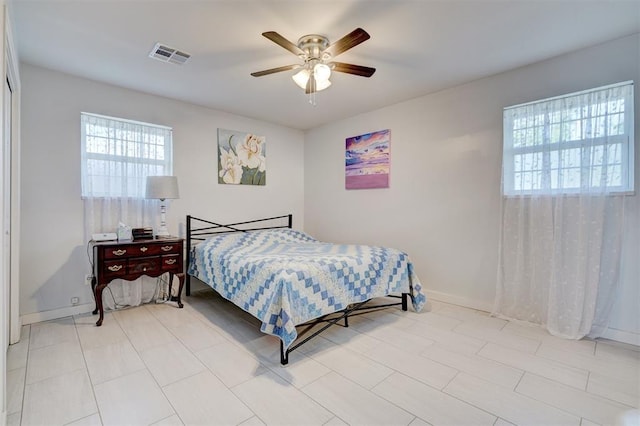 bedroom featuring ceiling fan, visible vents, baseboards, and multiple windows