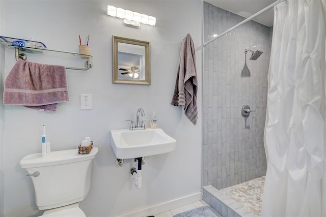 bathroom featuring tile patterned floors, a sink, ceiling fan, a tile shower, and toilet