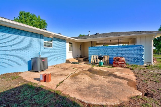 back of house featuring central AC unit, brick siding, and a patio