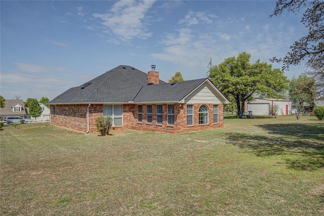 back of house with a chimney, brick siding, a yard, and a shingled roof