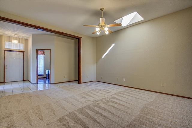 spare room with a skylight, baseboards, and light colored carpet