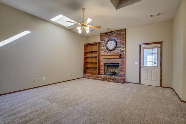 unfurnished living room featuring a ceiling fan, a skylight, carpet, a brick fireplace, and visible vents