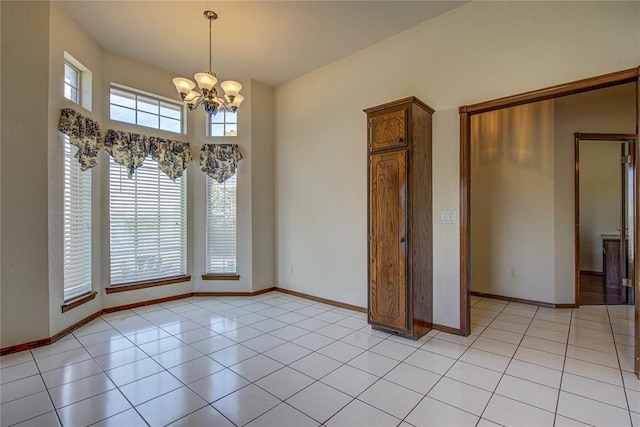 unfurnished dining area featuring light tile patterned floors, baseboards, and an inviting chandelier
