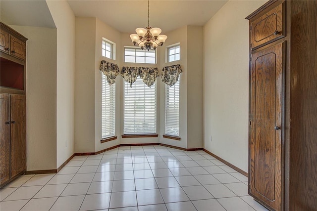 unfurnished dining area featuring baseboards, a chandelier, and light tile patterned floors