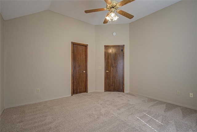 carpeted empty room with lofted ceiling, a ceiling fan, and baseboards