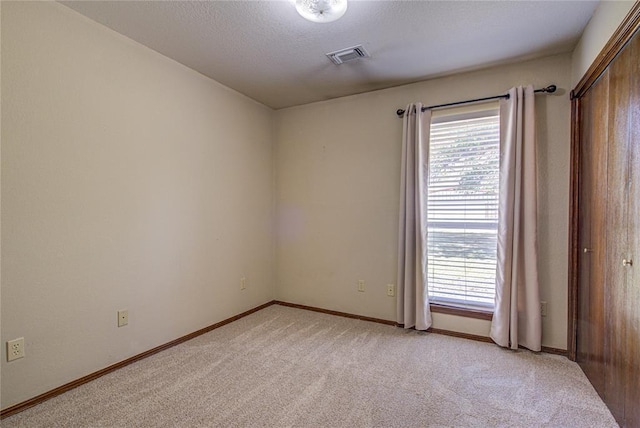 empty room featuring visible vents, baseboards, and light carpet