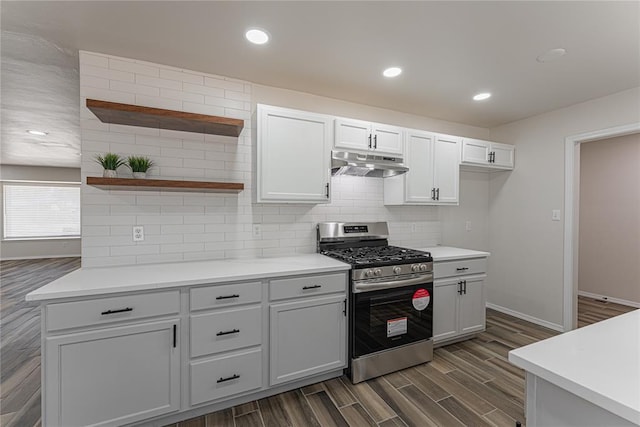 kitchen with under cabinet range hood, stainless steel gas stove, open shelves, light countertops, and tasteful backsplash
