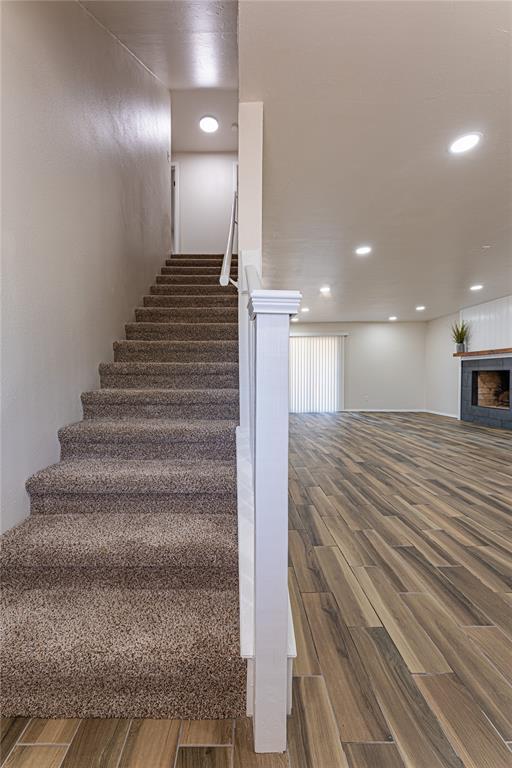 stairs with a tile fireplace, wood finished floors, and recessed lighting