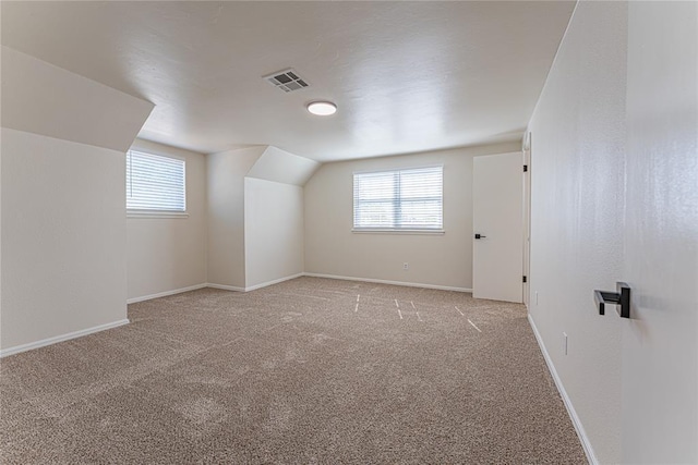 bonus room featuring lofted ceiling, visible vents, baseboards, and light carpet