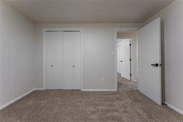 unfurnished bedroom featuring baseboards, carpet floors, and a closet