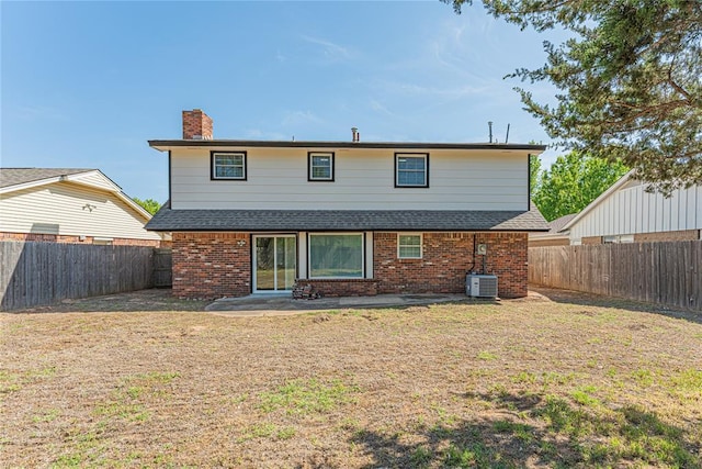 back of house with a patio area, a lawn, a shingled roof, a fenced backyard, and brick siding