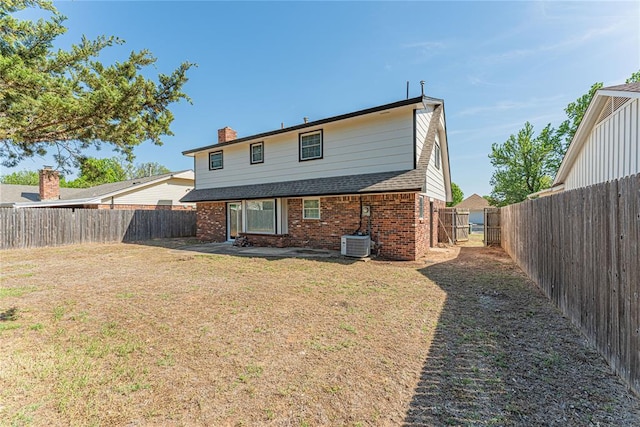 rear view of house with a fenced backyard, brick siding, a chimney, and a lawn