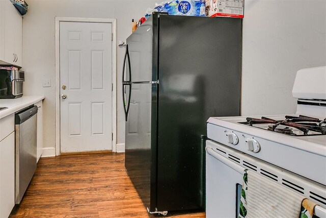 1115 W Eufaula St, Norman, OK 73069 - kitchen with stainless steel dishwasher, wood finished floors, white gas range oven, white cabinets, and freestanding refrigerator