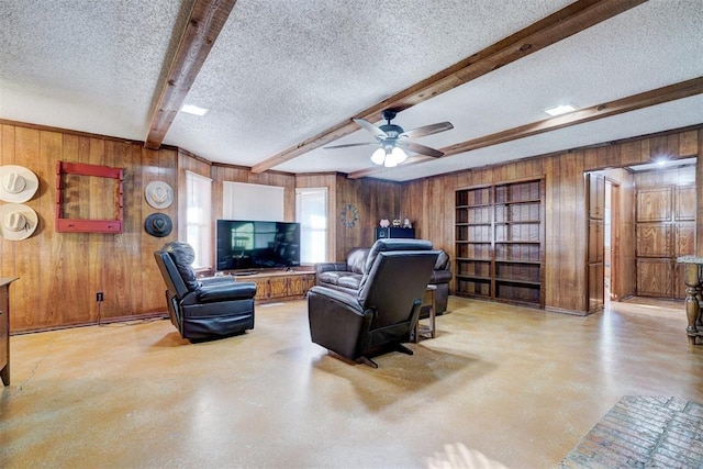 living room with ceiling fan, beam ceiling, a textured ceiling, and wooden walls