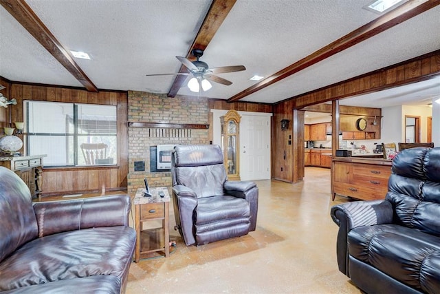 living room with beamed ceiling, wooden walls, a textured ceiling, and a ceiling fan