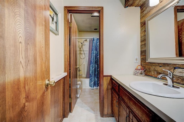 full bathroom with shower / tub combo, vanity, tile patterned floors, and a wainscoted wall