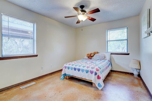 bedroom with ceiling fan, baseboards, a textured ceiling, and visible vents