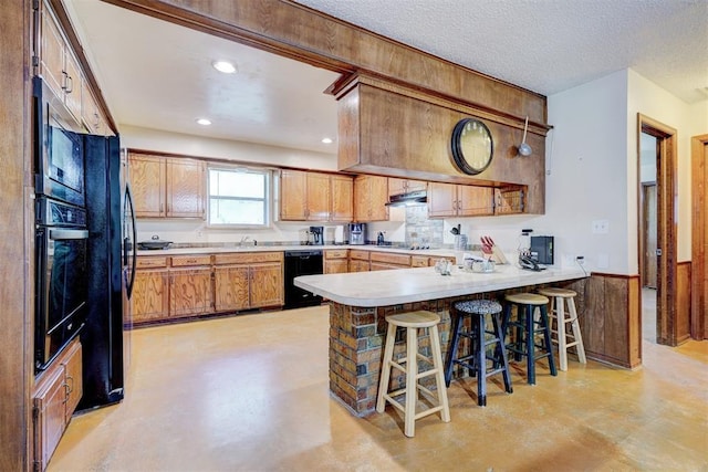 kitchen with black appliances, a peninsula, finished concrete floors, and light countertops