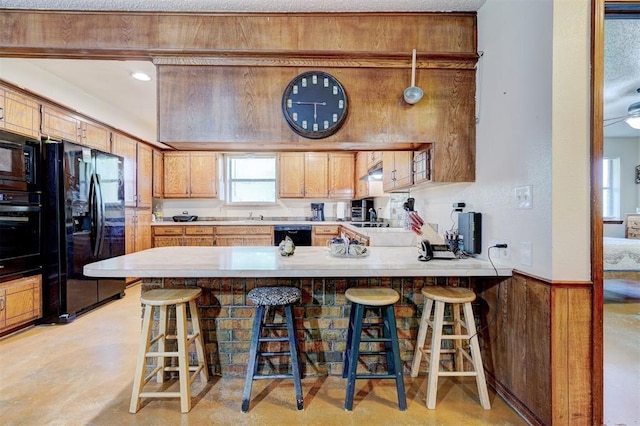 kitchen featuring a peninsula, light countertops, finished concrete floors, and black appliances