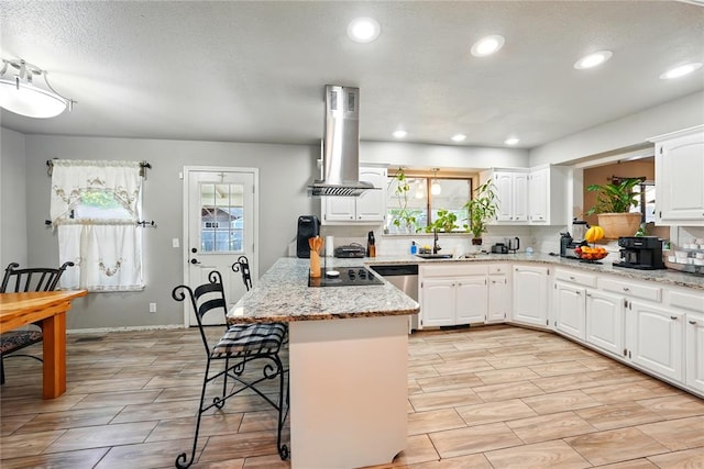 5029 NW 24th Pl, Oklahoma City, OK 73127 - kitchen with island exhaust hood, black electric stovetop, a kitchen bar, a peninsula, and white cabinetry