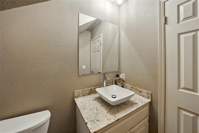 5029 NW 24th Pl, Oklahoma City, OK 73127 - bathroom with a textured wall, vanity, and toilet