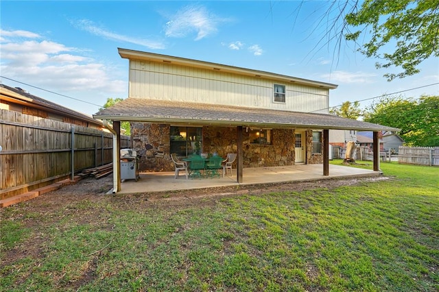 5029 NW 24th Pl, Oklahoma City, OK 73127 - back of house featuring stone siding, a lawn, a patio, and a fenced backyard