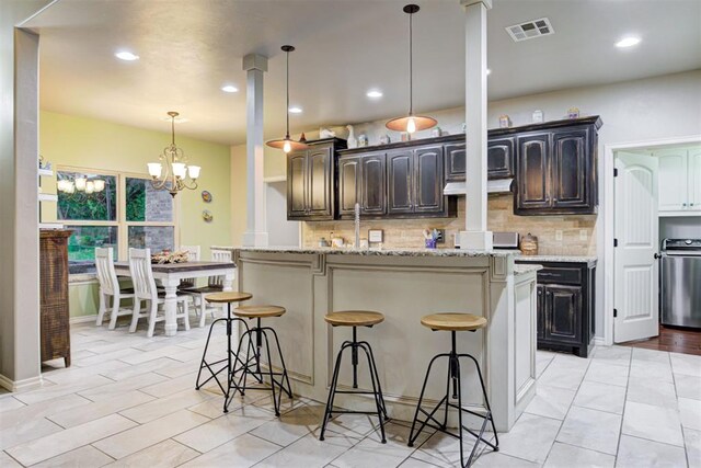 43855 Hunters Hill Dr, Shawnee, OK 74801 - kitchen featuring tasteful backsplash, a kitchen bar, a kitchen island with sink, a chandelier, and recessed lighting