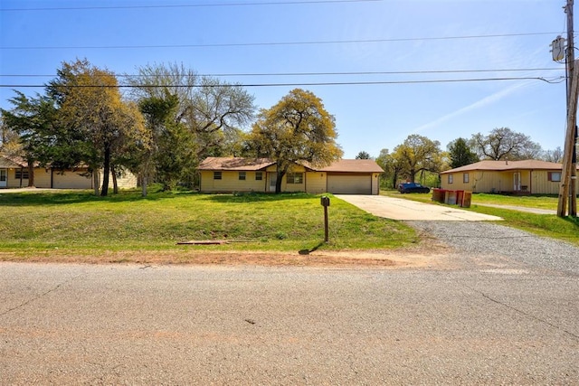 view of front of home featuring an attached garage, a front lawn, and driveway
