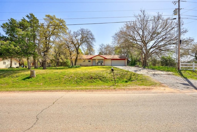 ranch-style home with an attached garage, driveway, a front yard, and fence