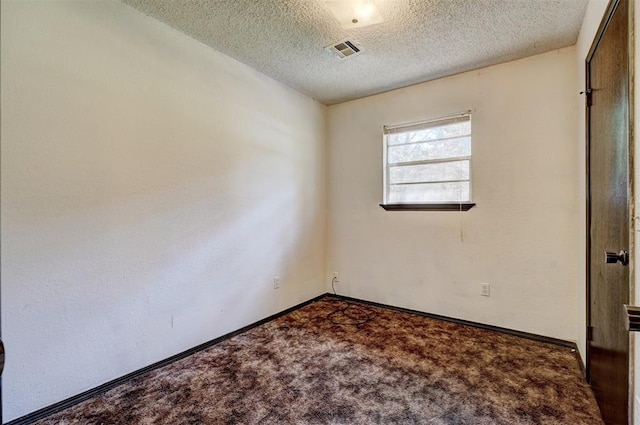 carpeted spare room with baseboards, a textured ceiling, and visible vents