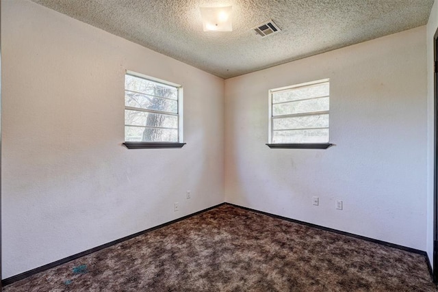 spare room with a textured ceiling, carpet, visible vents, and baseboards