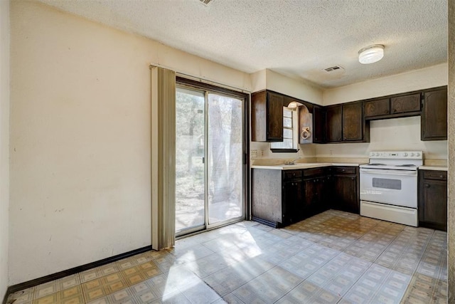 kitchen with dark brown cabinets, light floors, light countertops, electric range, and visible vents