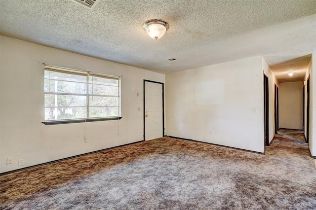 carpeted empty room with visible vents and a textured ceiling