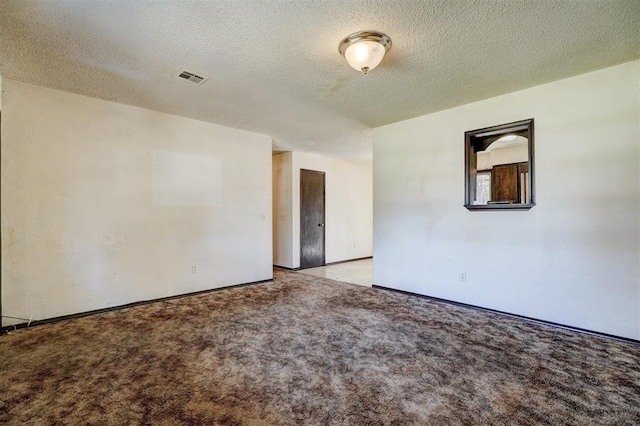 empty room with light colored carpet, baseboards, a textured ceiling, and visible vents