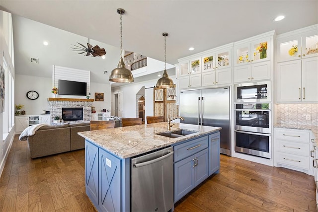 kitchen featuring a sink, white cabinets, a kitchen island with sink, dark wood-style flooring, and built in appliances