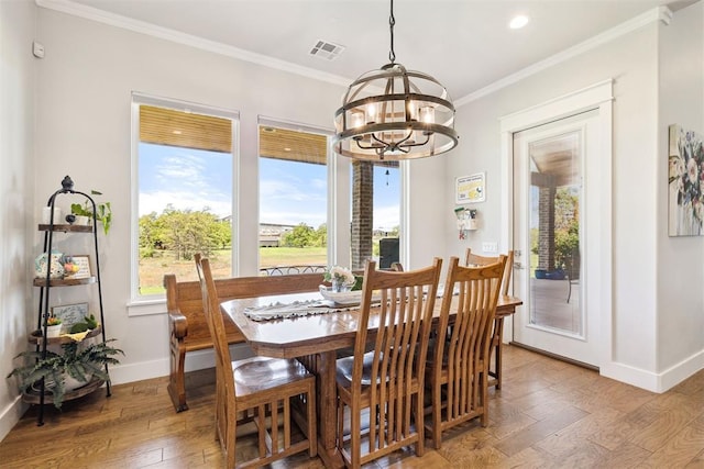 dining area featuring hardwood / wood-style floors, ornamental molding, visible vents, a chandelier, and baseboards