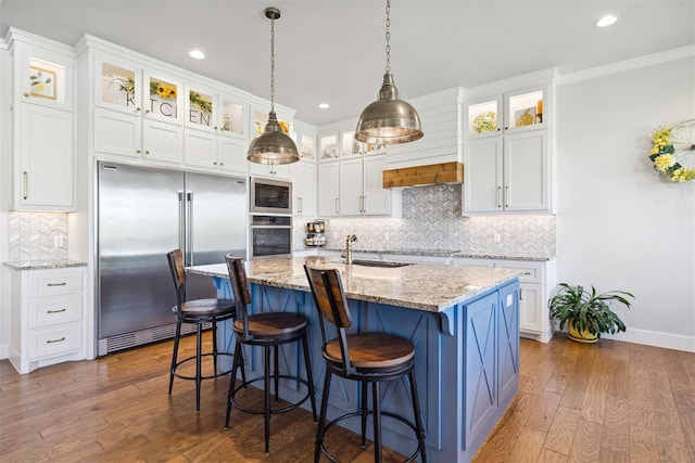 kitchen with built in appliances, recessed lighting, a sink, decorative backsplash, and white cabinets
