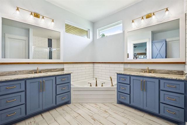 bathroom with a bath, tiled shower, two vanities, and a sink