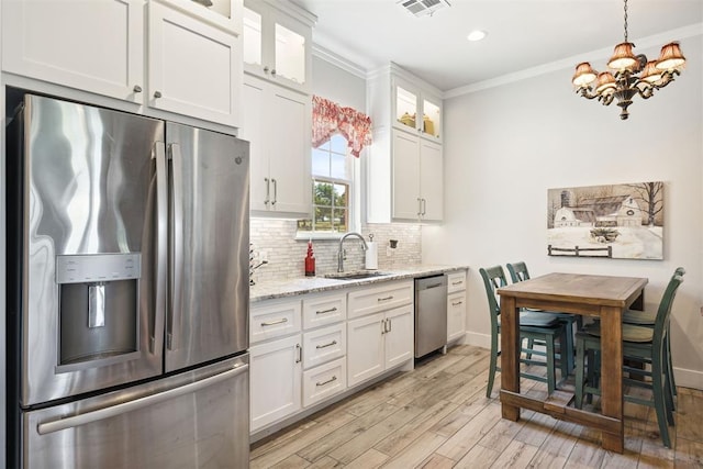 kitchen with a sink, white cabinetry, a chandelier, crown molding, and appliances with stainless steel finishes