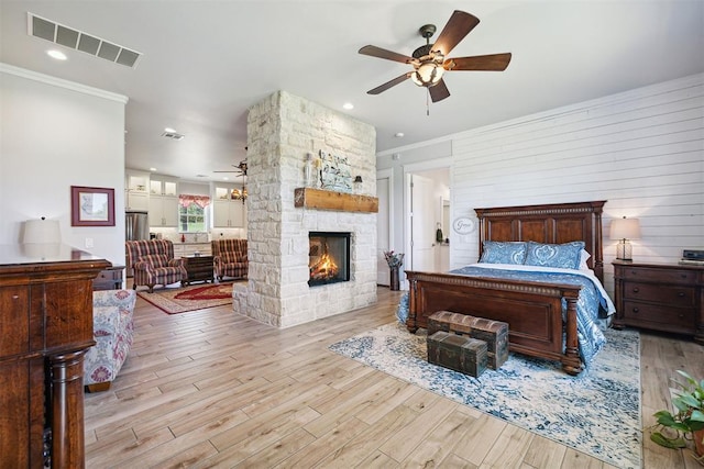 bedroom with ornamental molding, a fireplace, visible vents, and wood finished floors