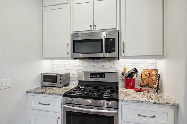 kitchen featuring backsplash, stainless steel appliances, white cabinets, and a toaster