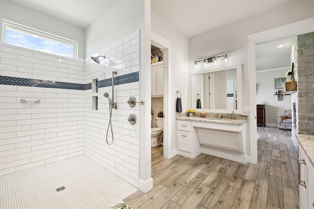 bathroom featuring vanity, toilet, tiled shower, and wood finished floors