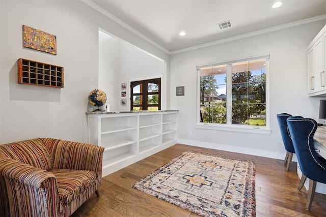 living area with wood finished floors, visible vents, baseboards, ornamental molding, and recessed lighting