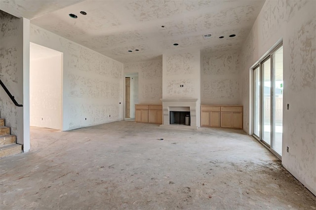 3825 Stone Hill Ln, Edmond, OK 73034 - unfurnished living room featuring plenty of natural light, a fireplace with raised hearth, and stairway