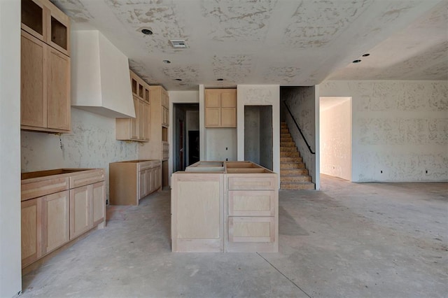 3825 Stone Hill Ln, Edmond, OK 73034 - kitchen featuring light brown cabinetry, concrete flooring, premium range hood, a center island, and glass insert cabinets
