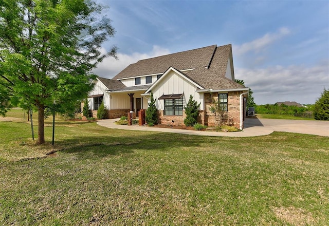 view of front of house with board and batten siding, brick siding, a shingled roof, and a front yard